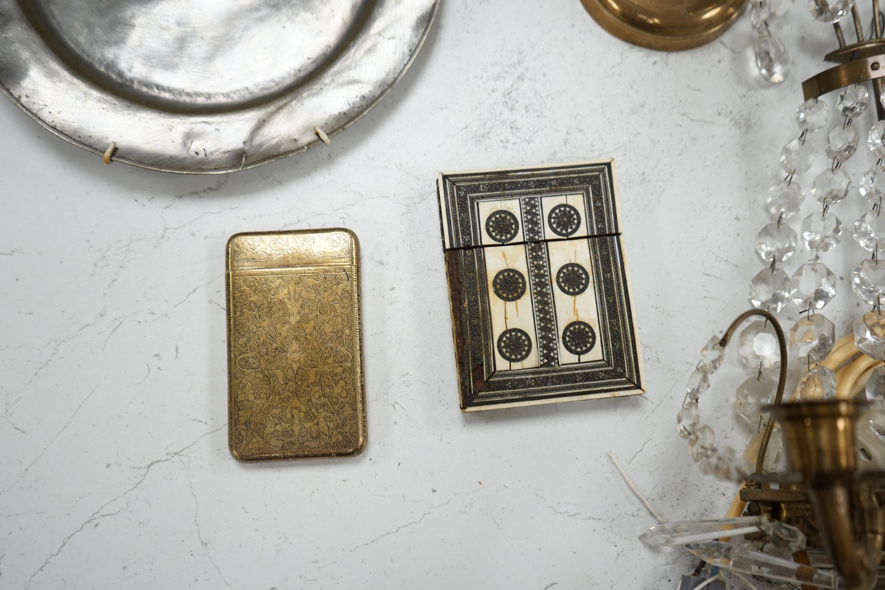 An embossed brass lamp, lustre drop wall light, a pair of bell-metal candlesticks, an 18th century pewter plate and a large Swedish embossed plaque